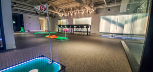 Indoor mini golf course with illuminated holes and a modern setting, showcasing a vibrant team-building environment for Chicago Mini Golf Rentals.