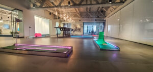 Portable mini golf course setup in a modern indoor space with illuminated putting greens, showcasing a team-building environment for Chicago Mini Golf Rentals.