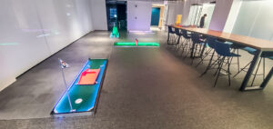 Portable mini golf setup featuring illuminated putting greens and a modern workspace environment, ideal for team-building events by Chicago Mini Golf Rentals.