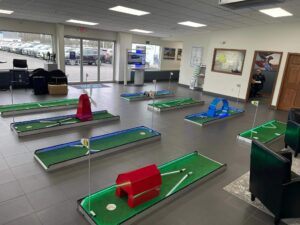 Mini golf course setup in a car dealership showroom, featuring colorful obstacles and putting greens, designed to create a family-friendly atmosphere and enhance customer engagement.