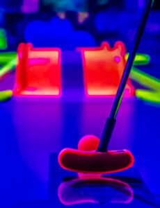 LED mini golf putter and ball in vibrant blue and pink lighting, showcasing the fun and engaging atmosphere of portable mini golf rentals for events.